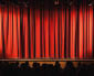 a closed red stage curtain in a small theater